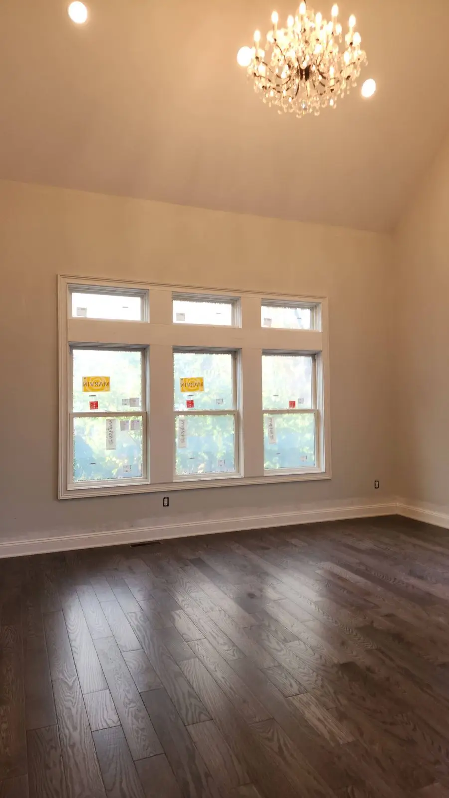Vaulted room with chandelier, triple window and dark wood floor